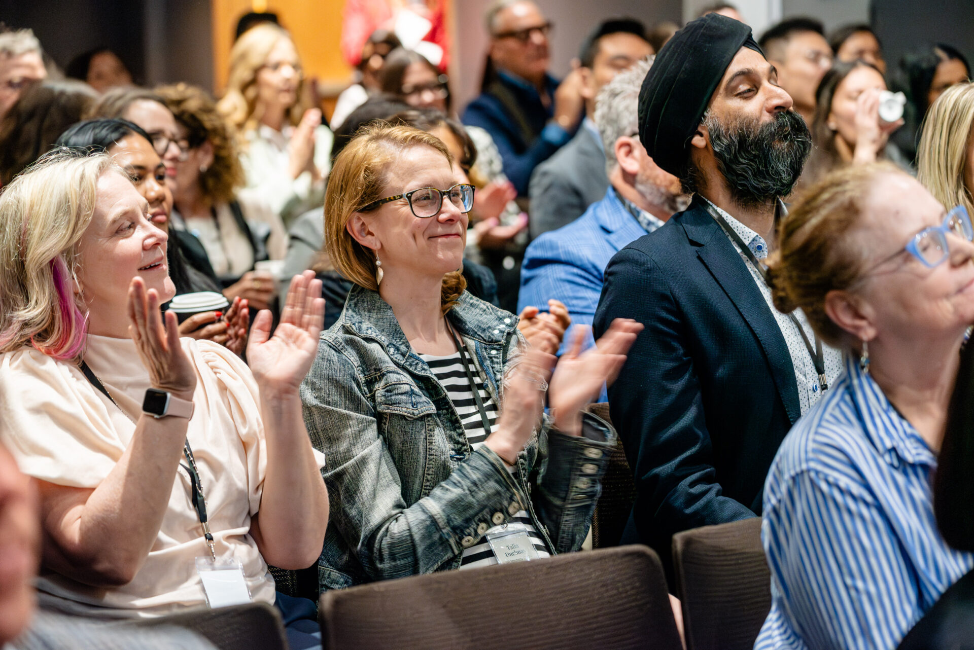 Audience smiling and clapping at the C-Suite Marketing Summit.